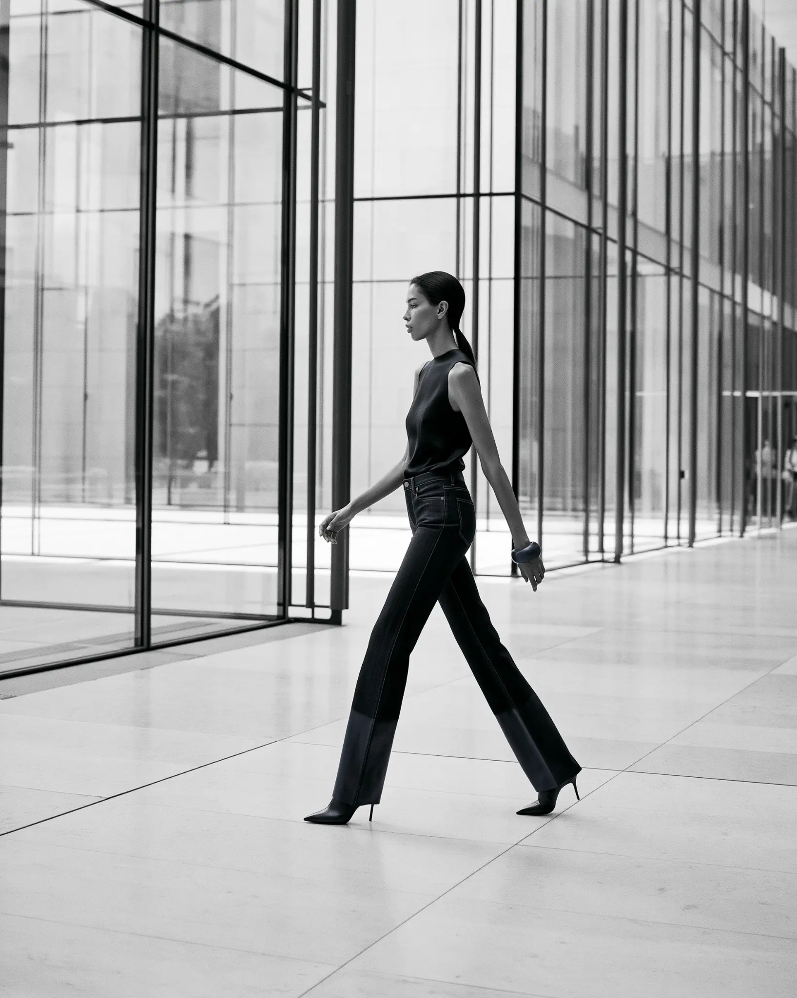 Monochrome architectural fashion study of indigo jeans with tonal leather hem panels